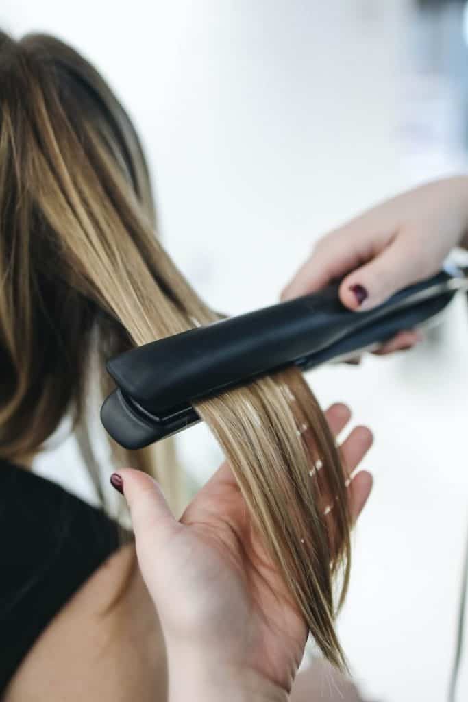 A person ironing a woman's hair